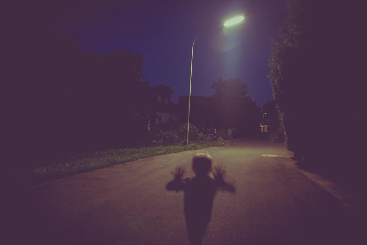 A lone child walking down the street at night A lone child walking down the street at night