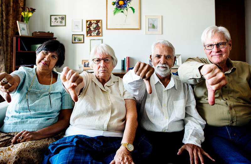 Group of senior friends gesturing thumbs down sign 