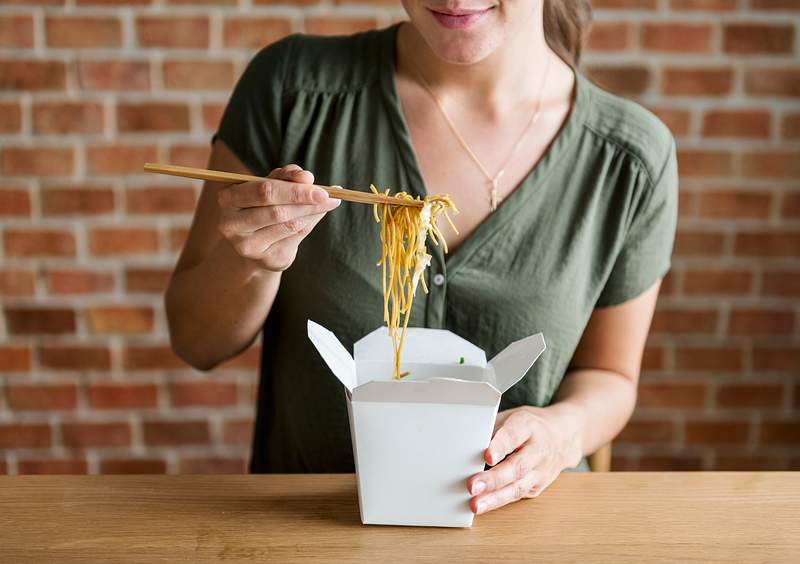Woman eating Chow mein with chopsticks