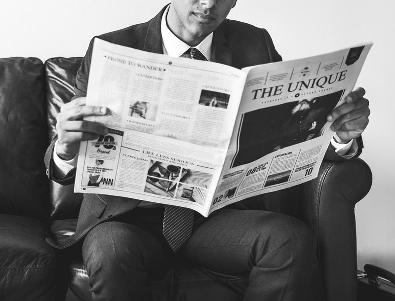 Businessman sitting and reading newspaper. 