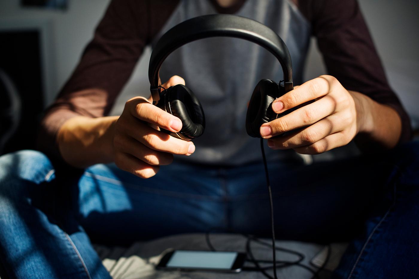 Teenage boy in a bedroom listening to music through his smartphone
