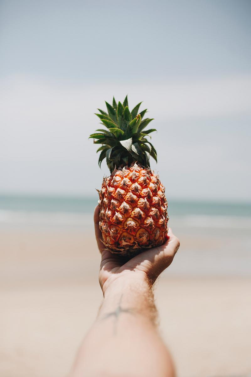 Pineapple at the beach Man holding a pineapple at the beach