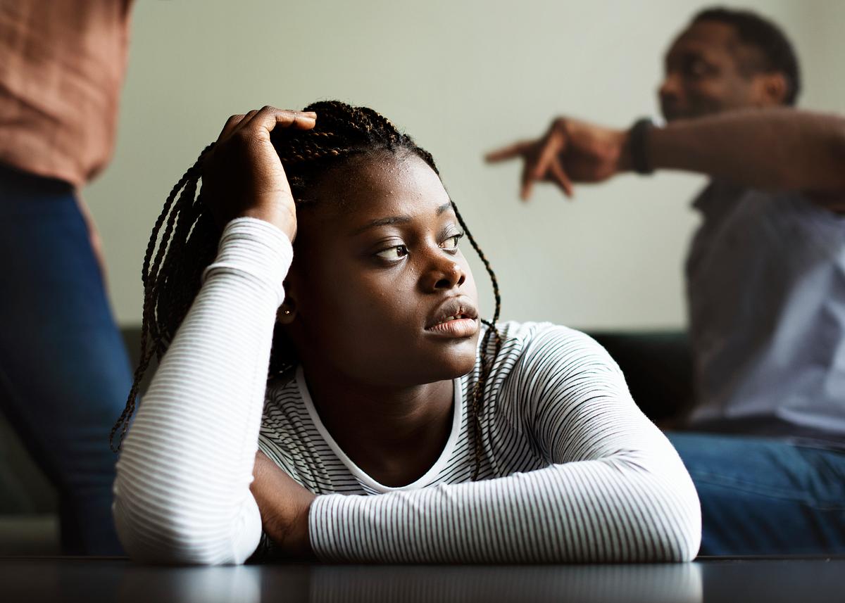 Daughter sitting sadly while her parents are fighting