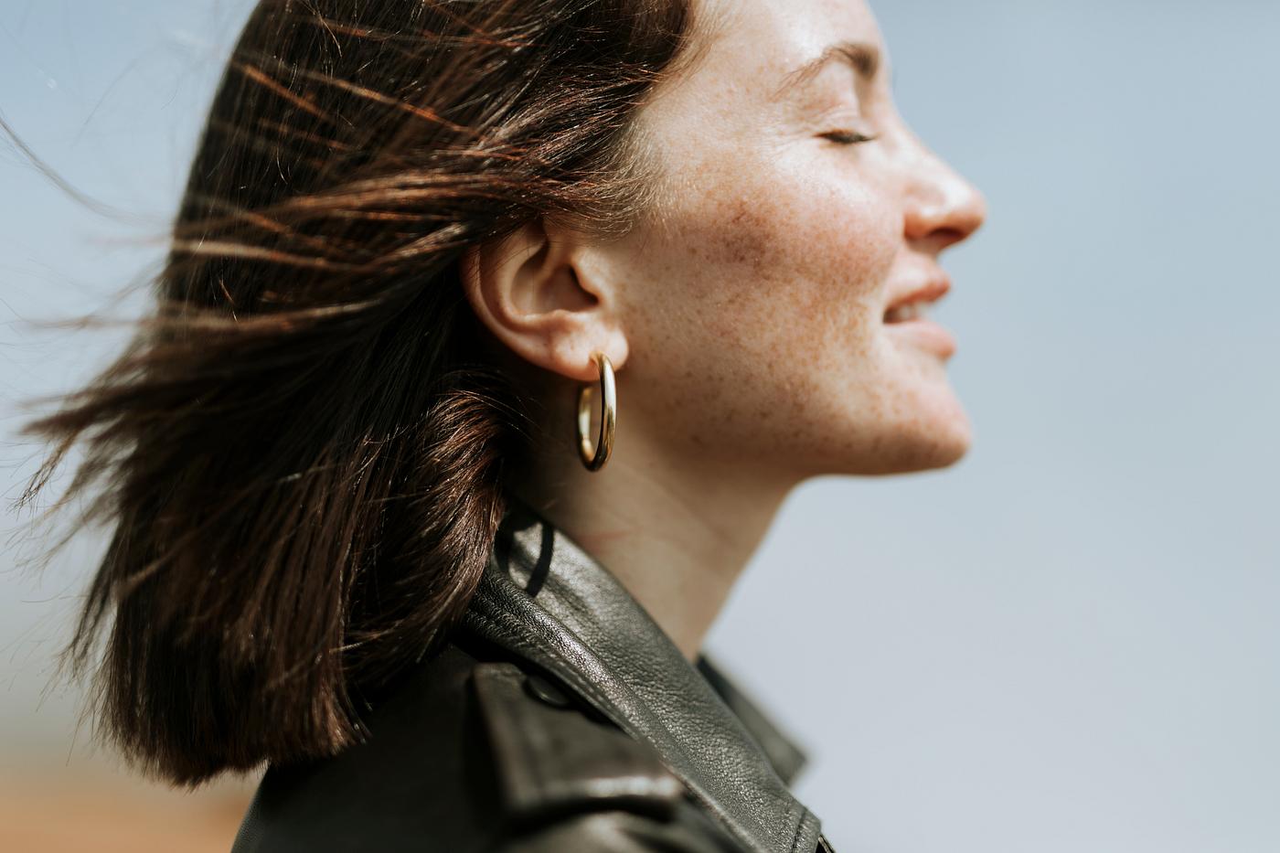 Side view of a woman in leather jacket standing in a park Side view of a woman in leather jacket standing in a park