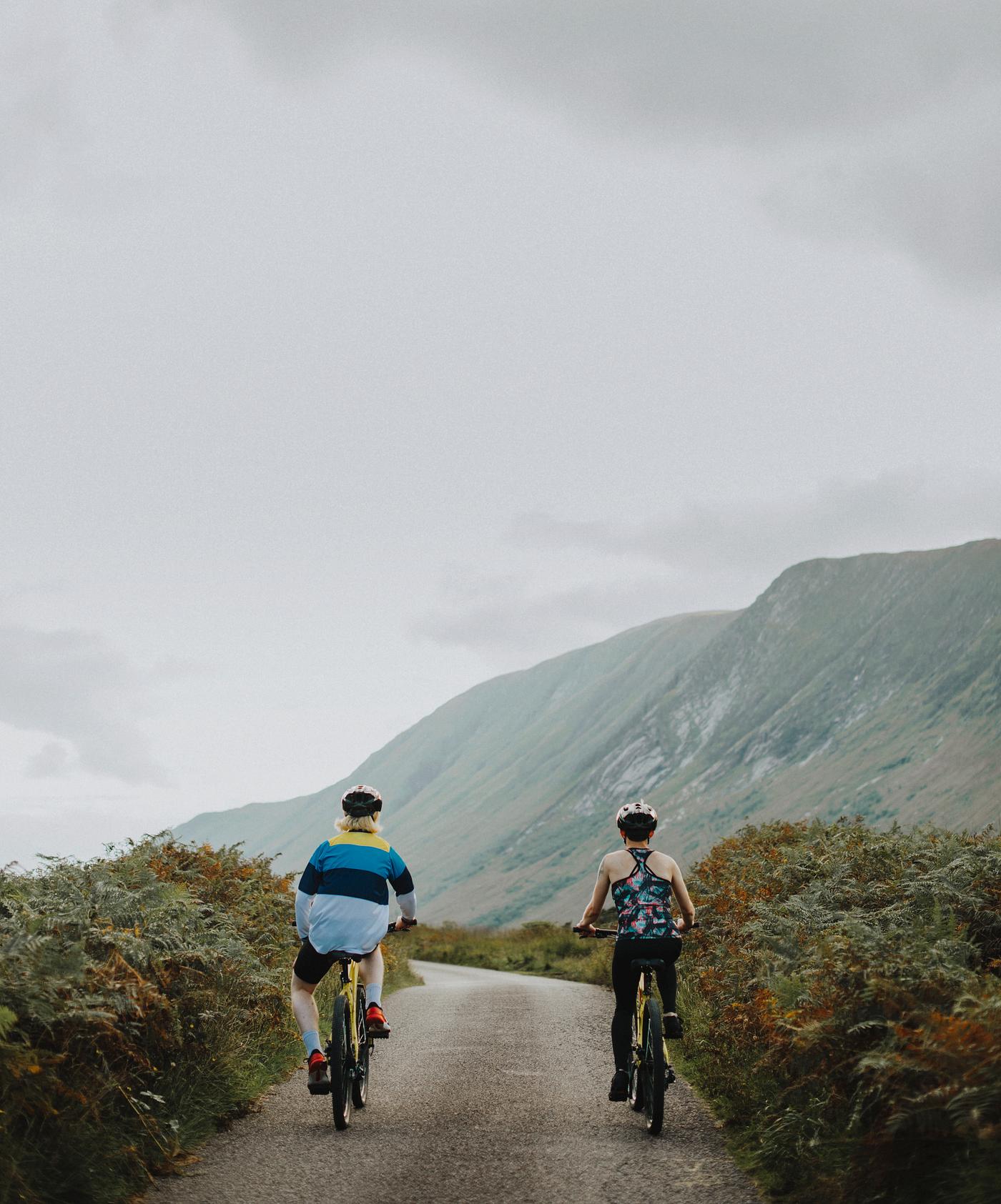Couple cycling down a road in the Scottish Highlands - active, activity, back, ballachulish, bicycle, bike, biking,... Couple cycling down a road in the Scottish Highlands - active, activity, back, ballachulish, bicycle, bike, biking,...