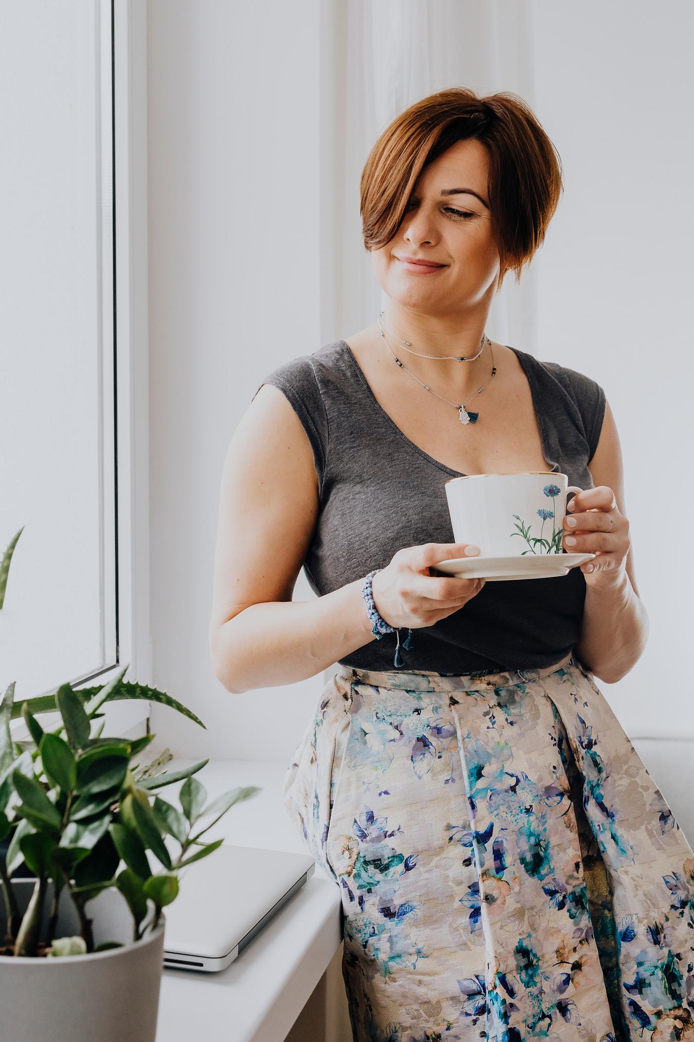 Woman holding a cup of tea by the window Woman holding a cup of tea by the window