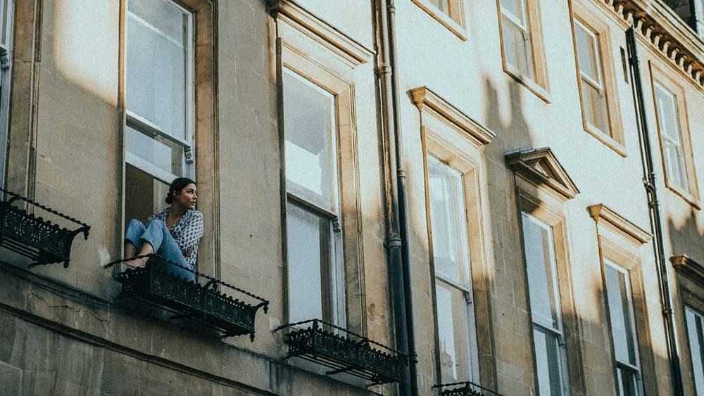 Woman in the window of her apartment during self quarantine due to the covid-19 pandemic in Britain. APRIL 4, 2020 - BATH, UK