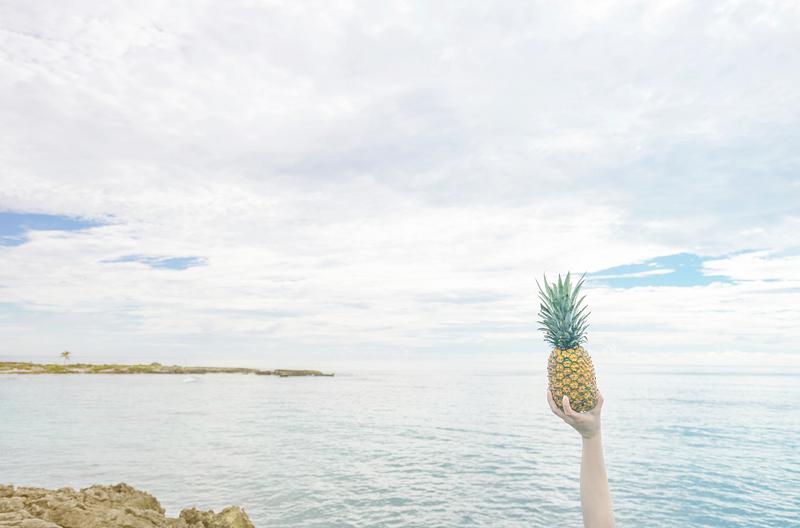 Someone holding a pineapple up in the air Someone holding a pineapple up in the air