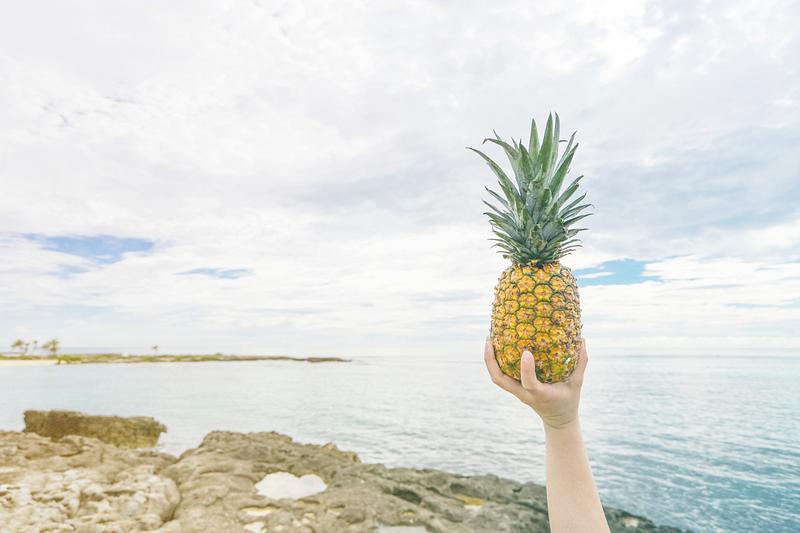 Someone holding a pineapple up in the air Someone holding a pineapple up in the air