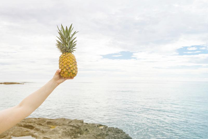Someone holding a pineapple up in the air Someone holding a pineapple up in the air