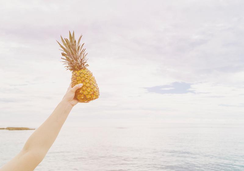 Someone holding a pineapple up in the air Someone holding a pineapple up in the air