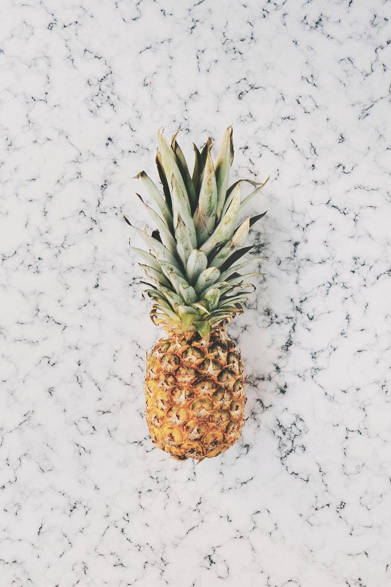 Ripe pineapple on a marble slate Ripe pineapple on a marble slate