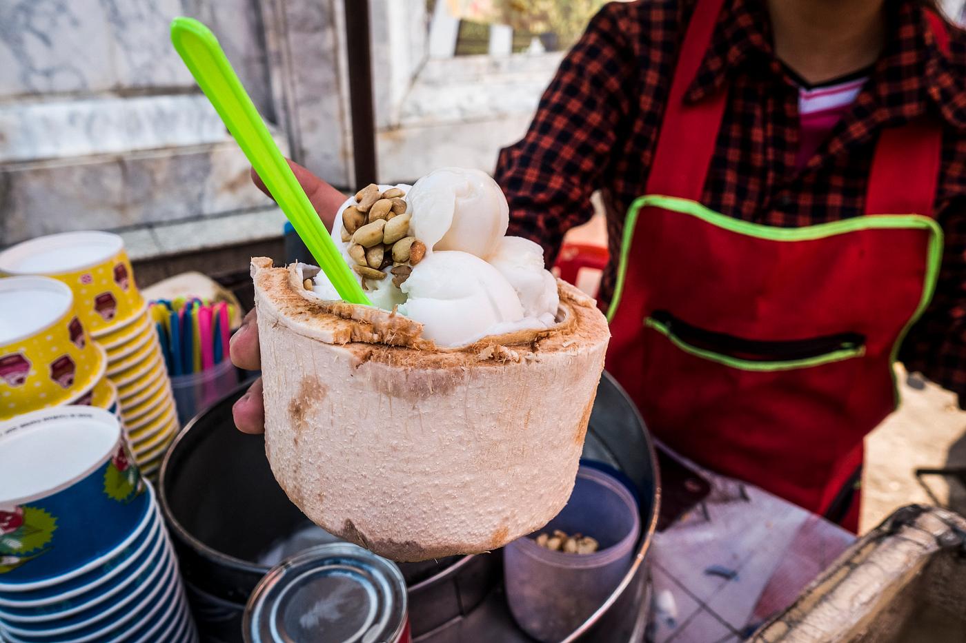 Woman serving fresh coconut ice cream in young coconut Woman serving fresh coconut ice cream in young coconut