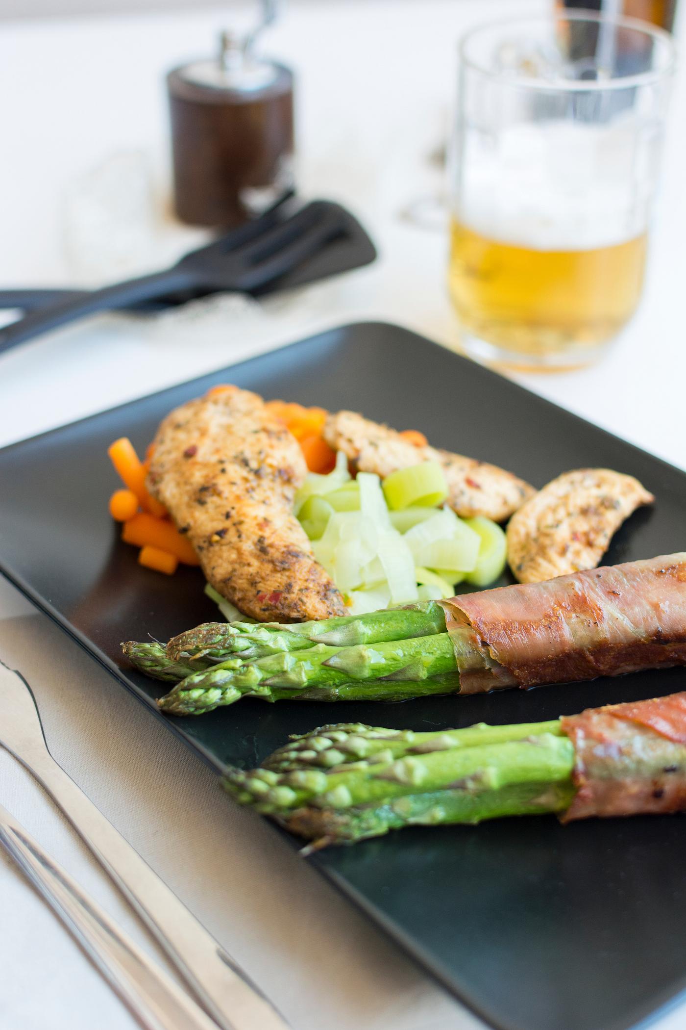 Chicken breast with bacon-wrapped asparagus and a glass of beer Chicken breast with bacon-wrapped asparagus and a glass of beer