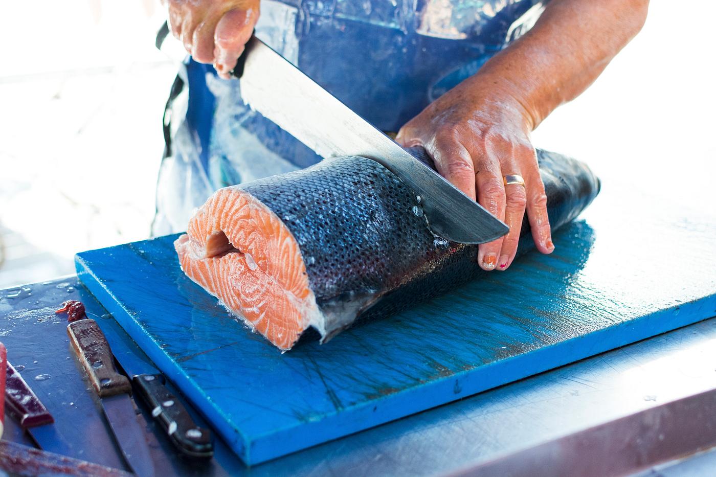 Fresh salmon being sliced at a market Fresh salmon being sliced at a market