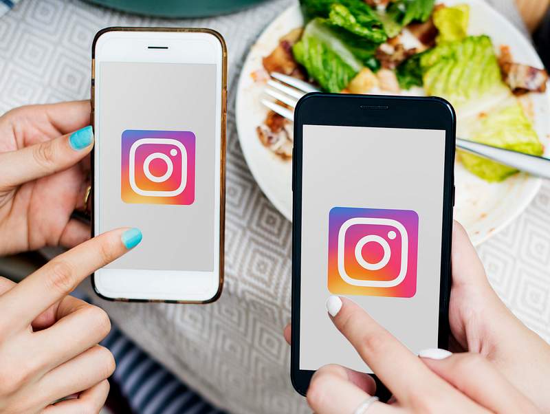 How To Master Instagram Restaurant Marketing in 2021 4 Friends using Instagram on mobile phones in a restaurant