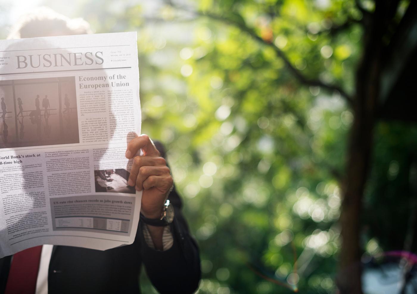 Businessman standing and reading newspaper Businessman standing and reading newspaper