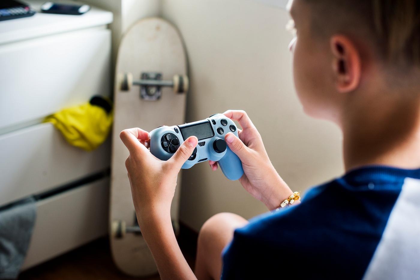 Young caucasian boy holding game control sitting on bed Young caucasian boy holding game control sitting on bed