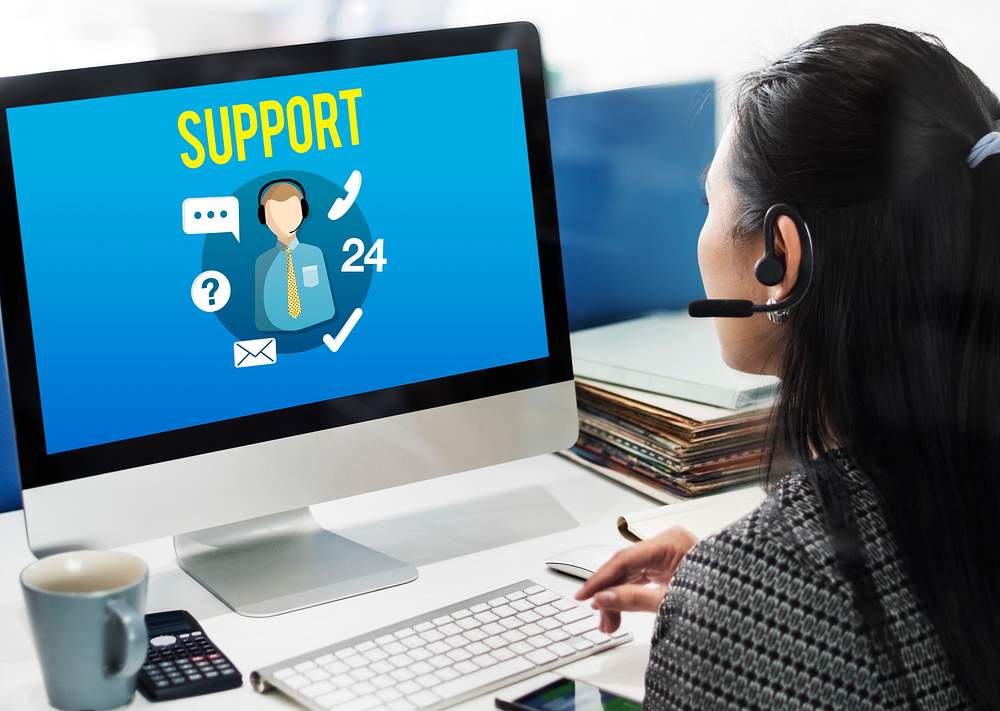 A lady on a computer at a company's call center helping customers out over the phone