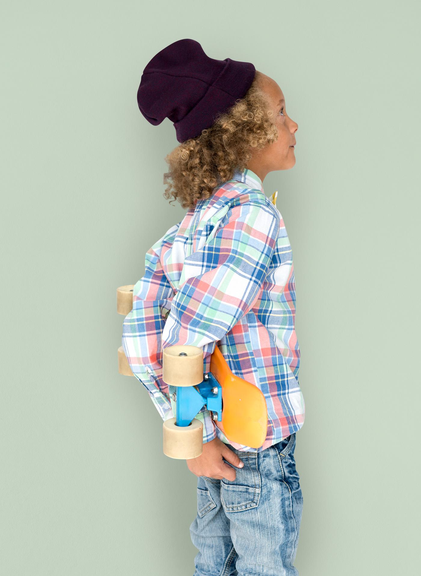 Boy holding a skateboard behind his back Boy holding a skateboard behind his back