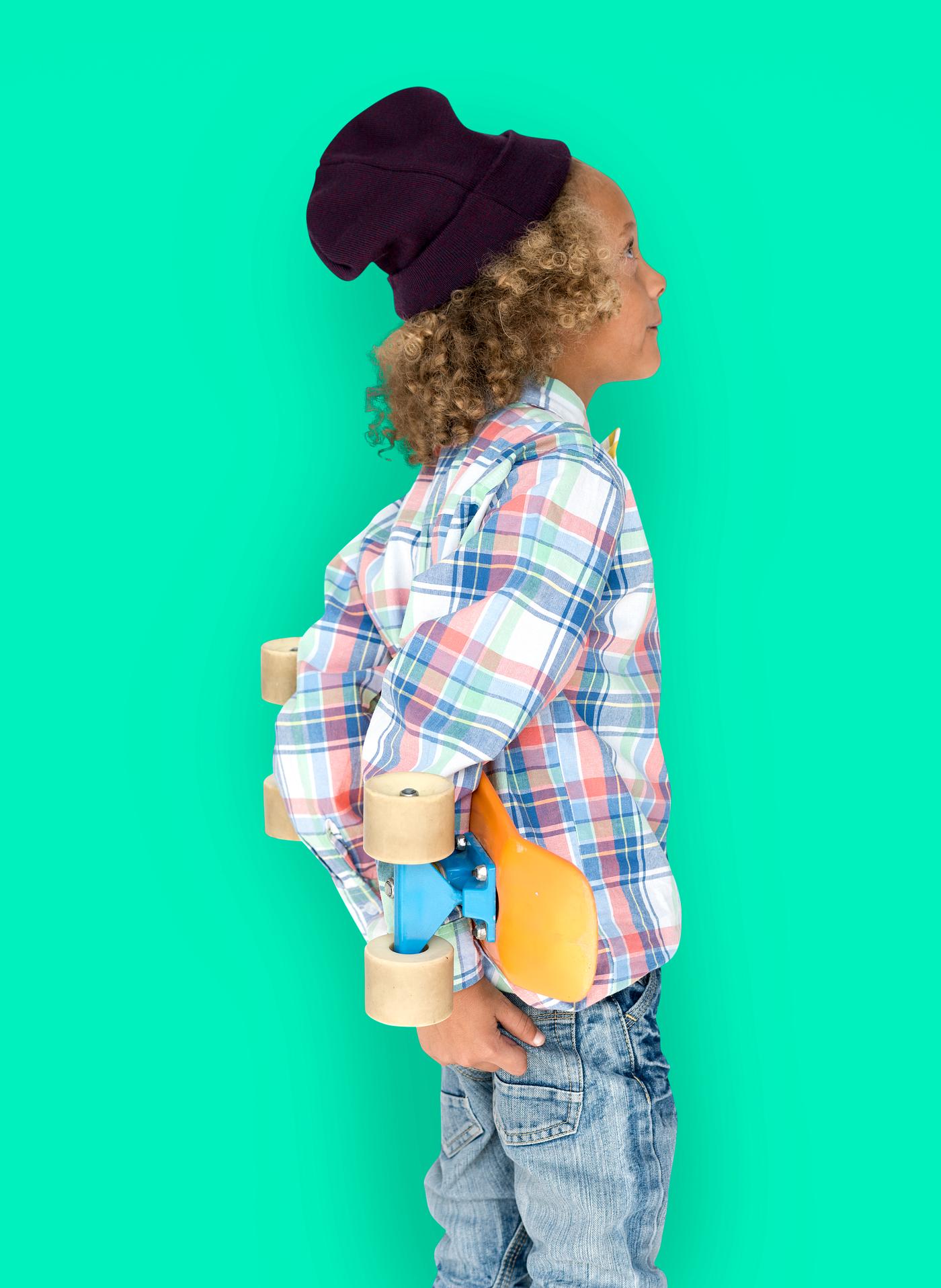 Boy holding a skateboard behind his back Boy holding a skateboard behind his back