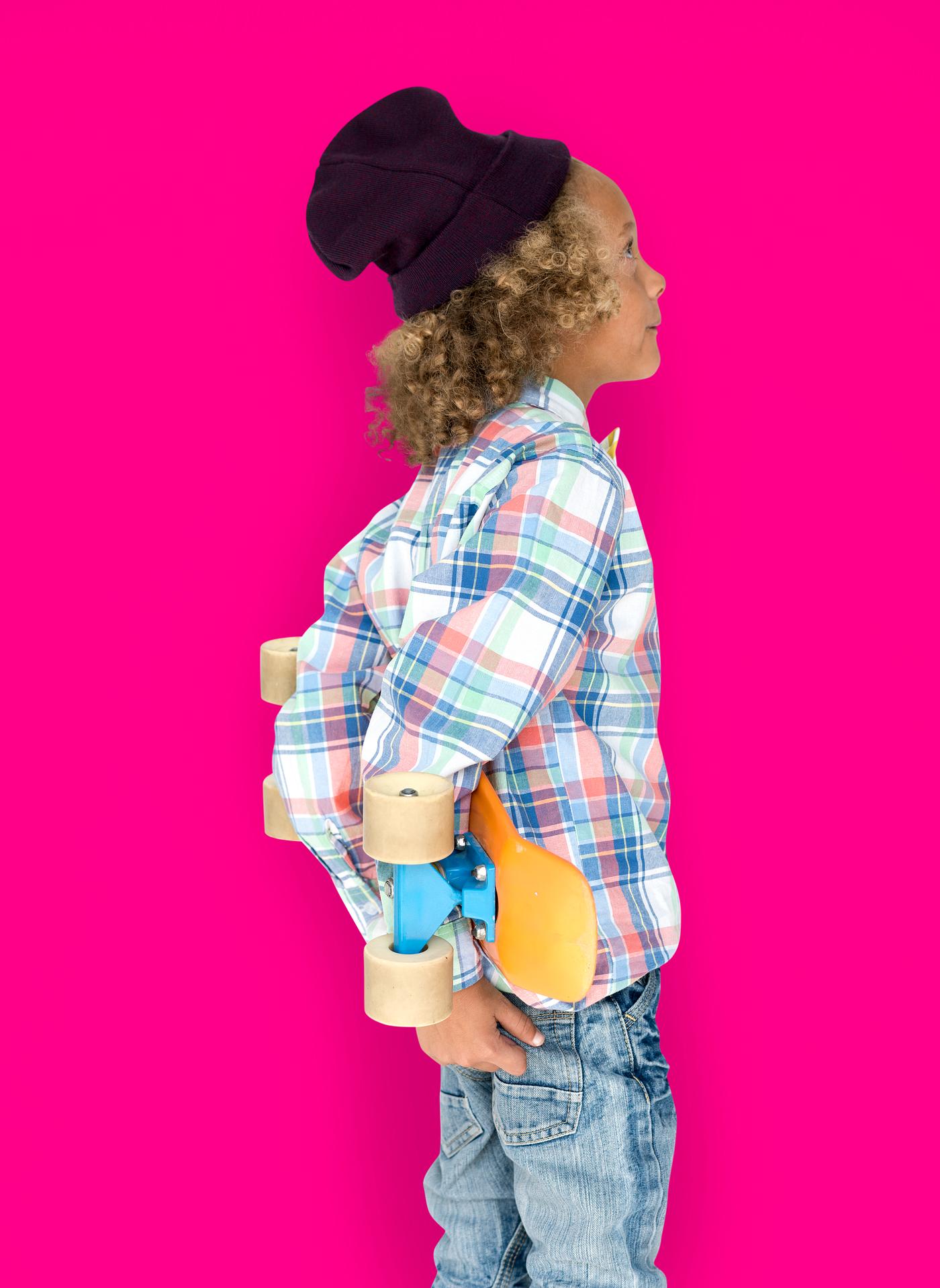 Boy holding a skateboard behind his back Boy holding a skateboard behind his back