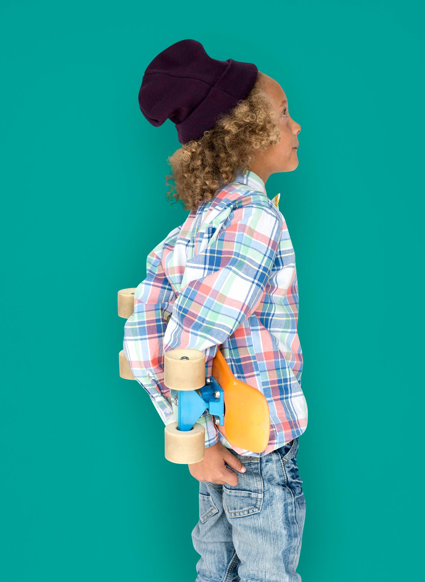 Boy holding a skateboard behind his back Boy holding a skateboard behind his back