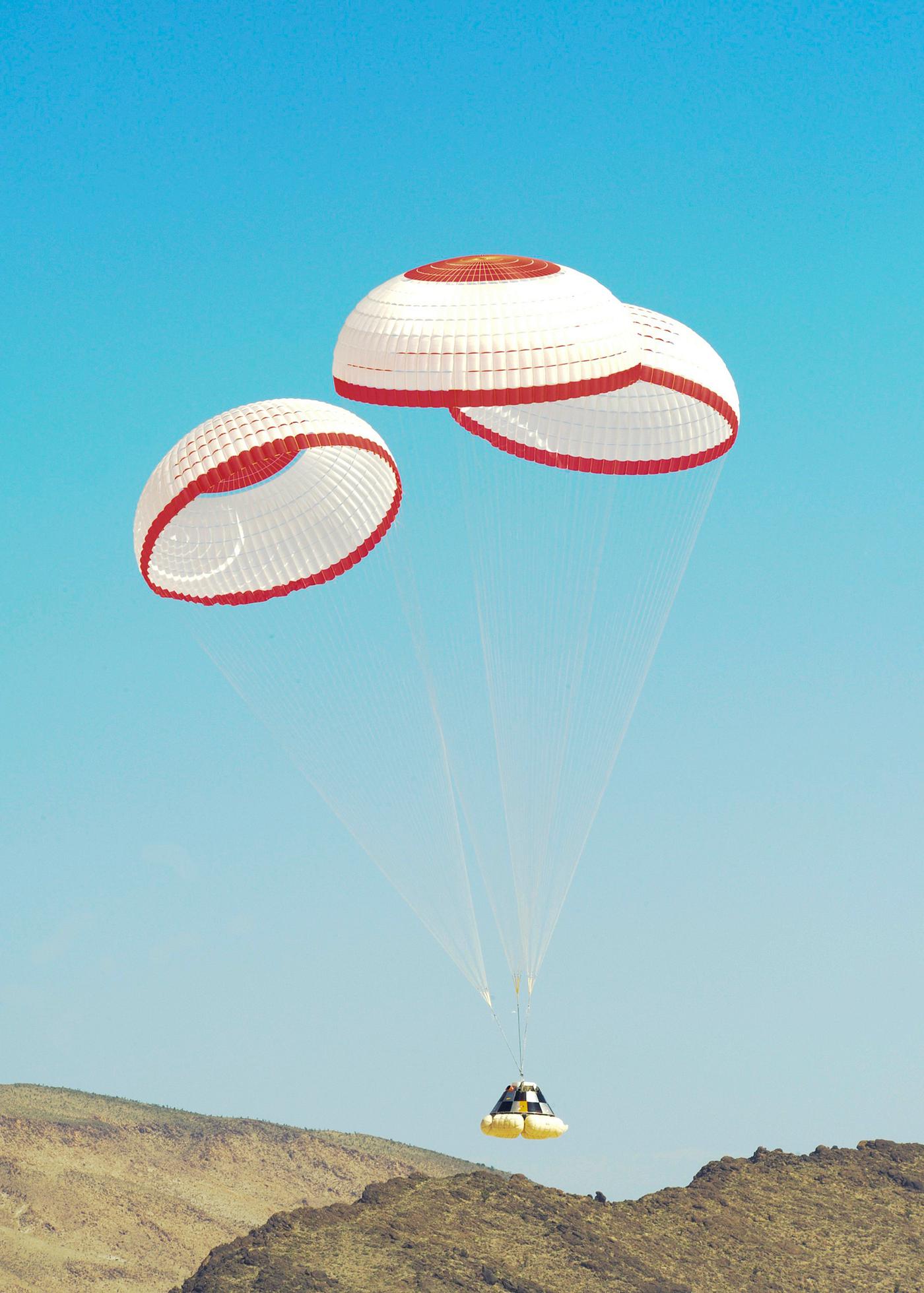 The Boeing Company's CST-100 crew capsule floats to a smooth landing beneath three main parachutes over the Delamar Dry... The Boeing Company's CST-100 crew capsule floats to a smooth landing beneath three main parachutes over the Delamar Dry...