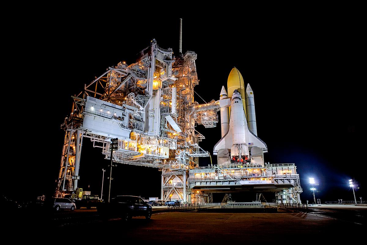 Space shuttle Discovery stands tall on Launch Pad 39A at NASA's Kennedy Space Center in Florida as space center workers prepare to move the rotating service structure into place. Original from NASA. Digitally enhanced by rawpixel.