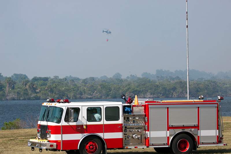 At NASA's Kennedy Space Center in Florida, a… | Free public domain photo At NASA's Kennedy Space Center in Florida, a helicopter collects water from the Turn Basin to douse a nearby brush fire, 27…