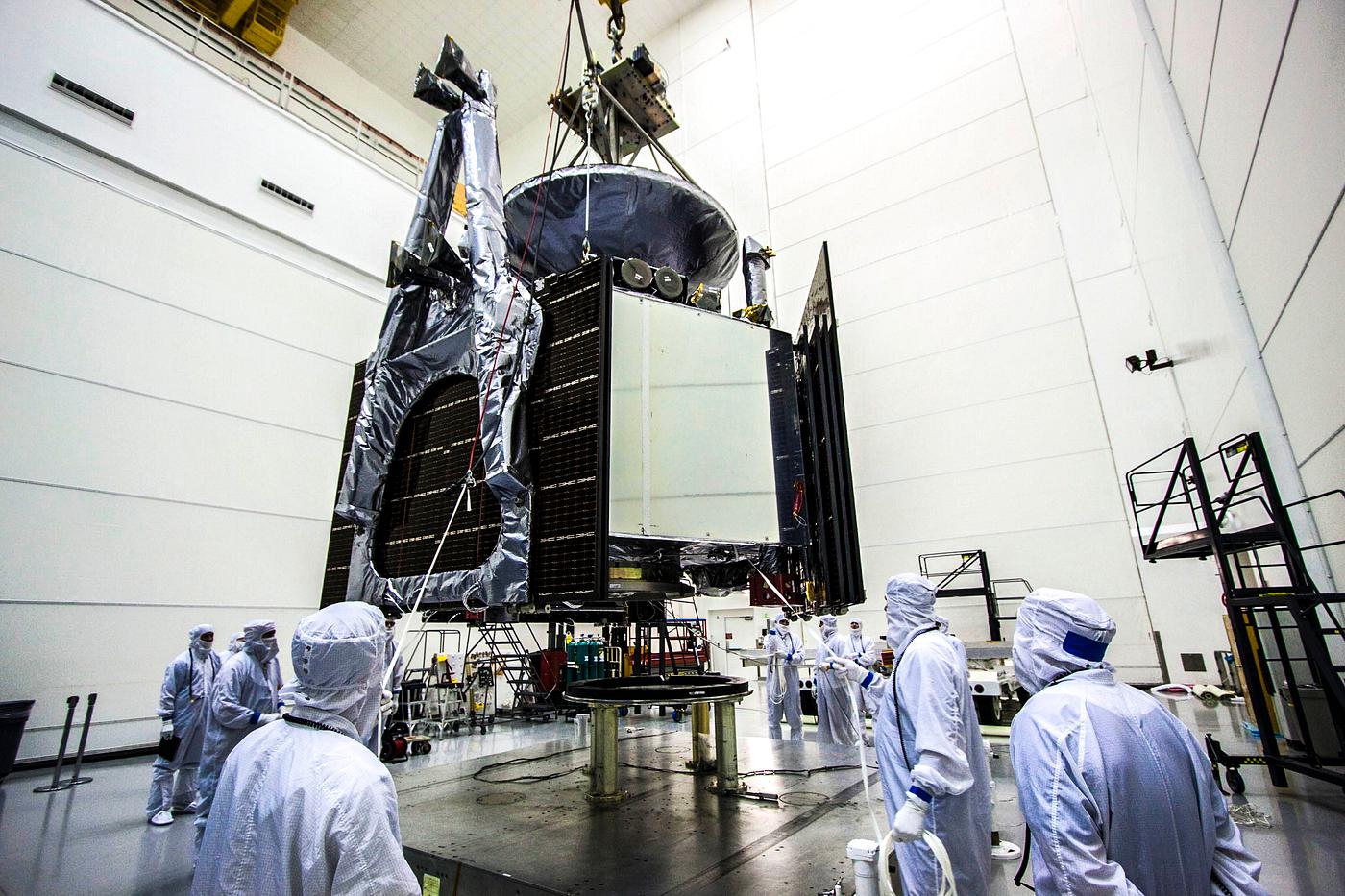 Technicians use an overhead crane to lower NASA Juno spacecraft onto a fueling stand where the spacecraft will be loaded... Technicians use an overhead crane to lower NASA Juno spacecraft onto a fueling stand where the spacecraft will be loaded...