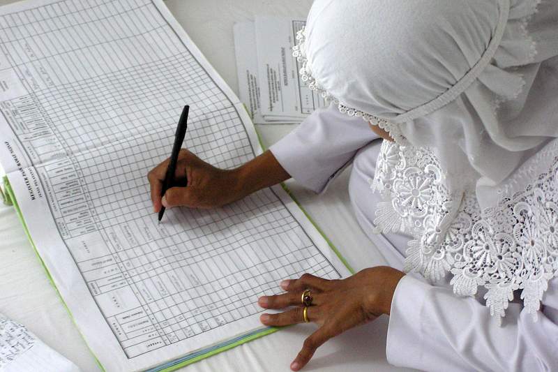 An Indonesian midwife entering birth data in a new log book at University Hospital, in Banda Ache, after the Sumatra tsunami…
