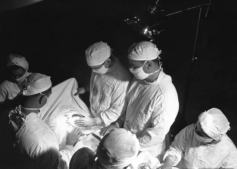 The 1950s historical photograph of the inside of an operating room suite during a surgical procedure. Original image sourced…