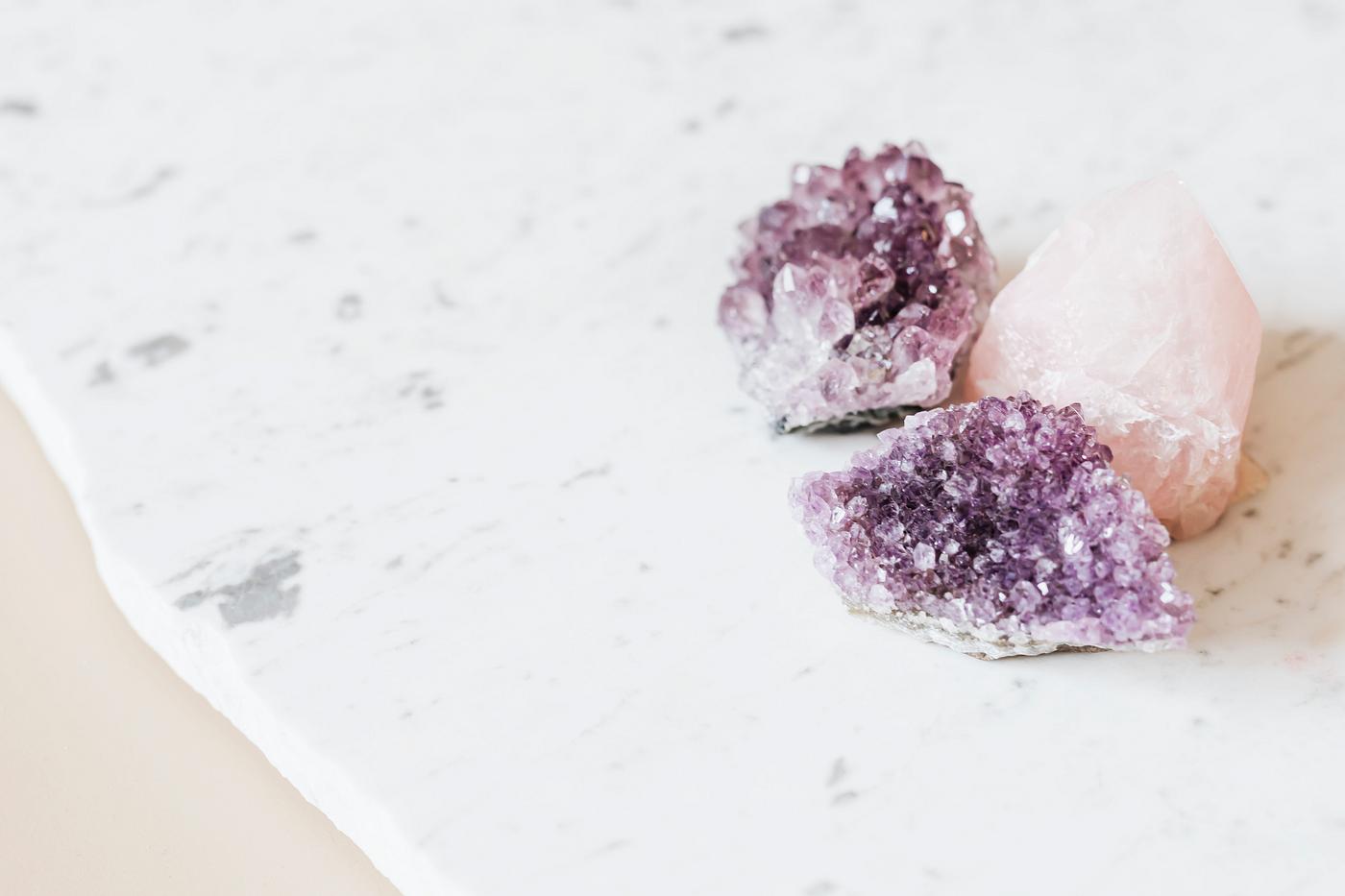 Rose Quartz And Amethyst Healing Crystals On A Marble Countertop