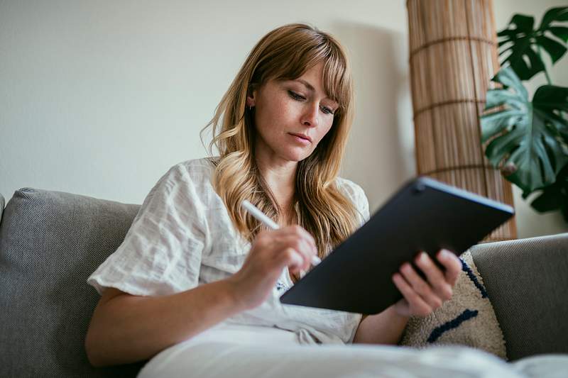 Woman using a stylus writing on a digital tablet during coronavirus quarantine
